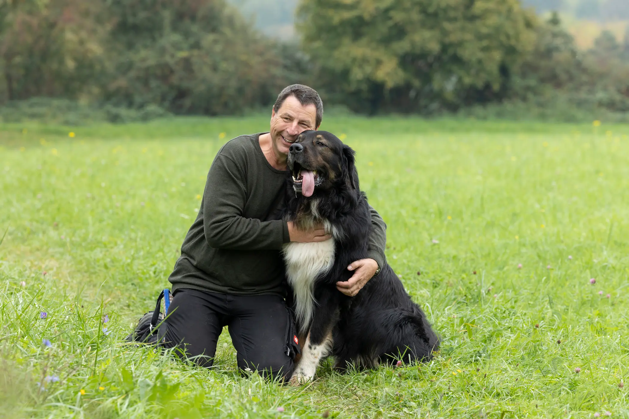 Thorsten Lapsit sitzt entspannt mit einem Hund auf einer Wiese