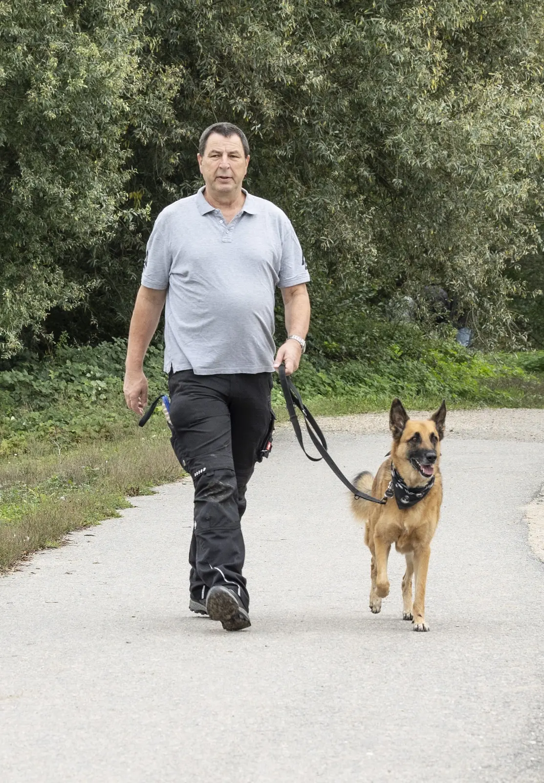 Thorsten Lapsit geht mit dem Malinois entspannt an lockerer Leine einen Weg entlang
